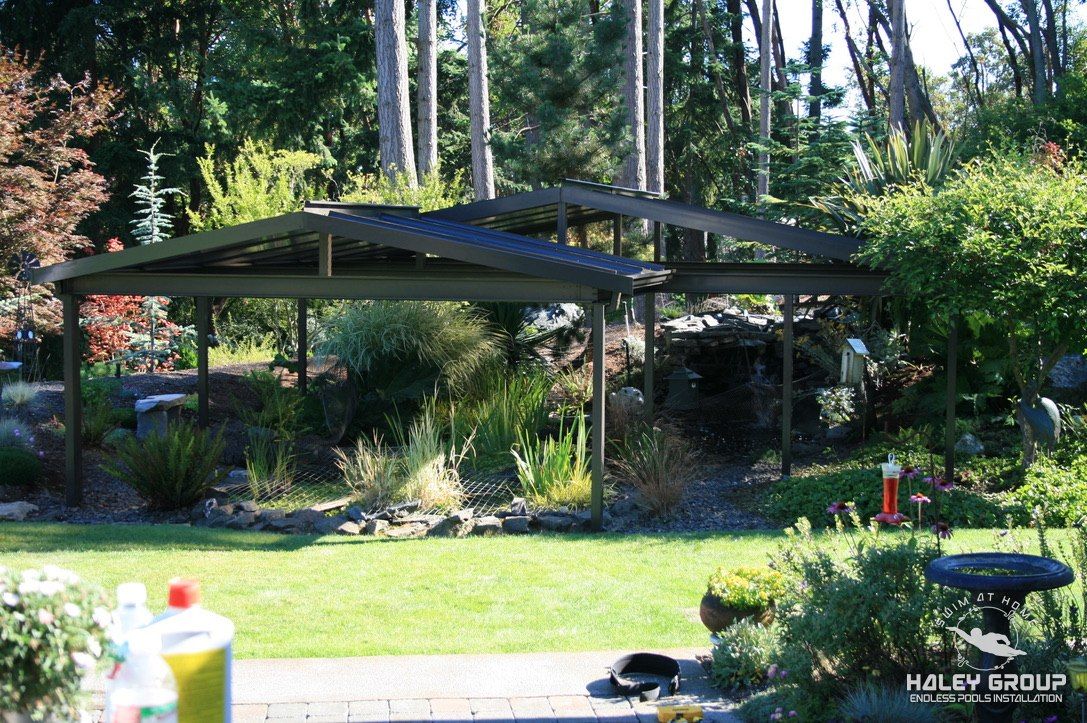Bronze-framed garden canopies with translucent roofs over a landscaped garden