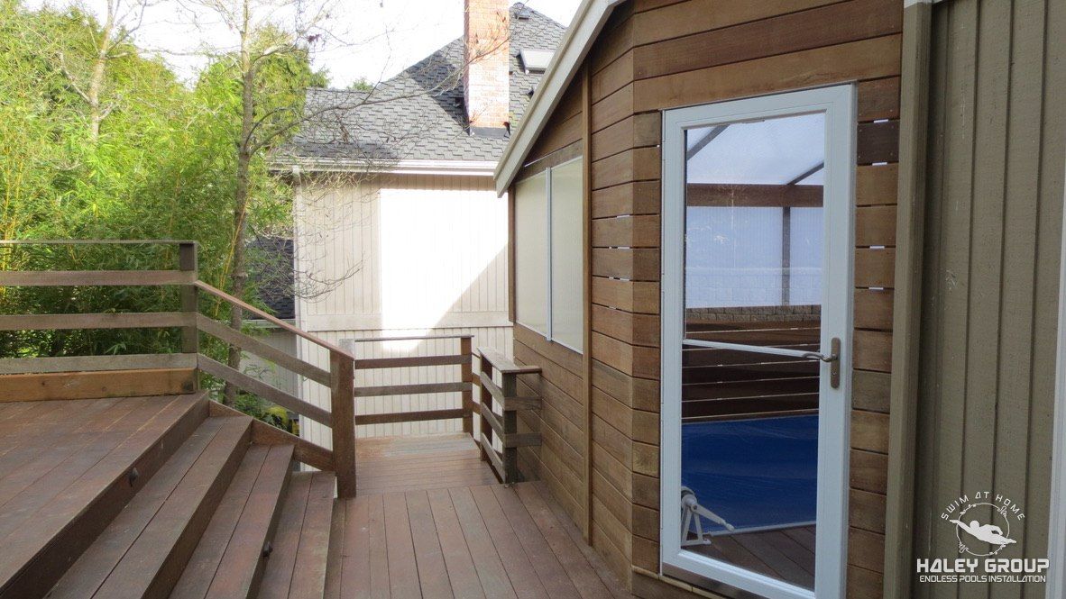 Deck stairs and the enclosure door, with the pool visible through the glass