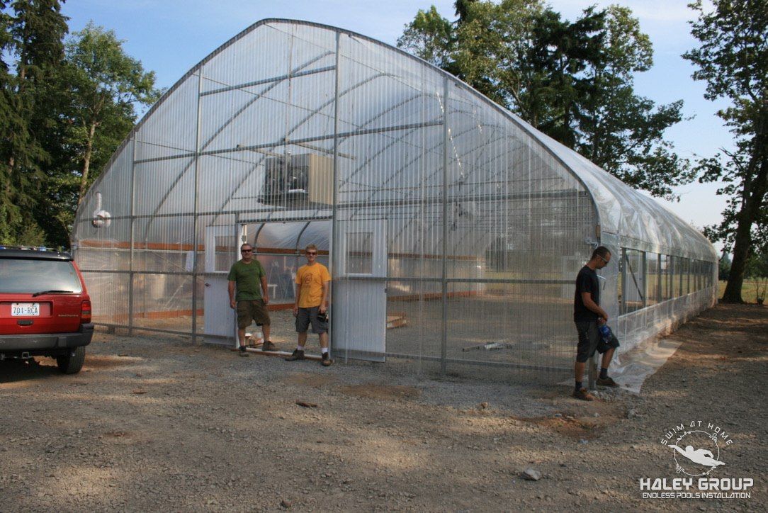 Crew in front of a newly finished gothic-arch greenhouse