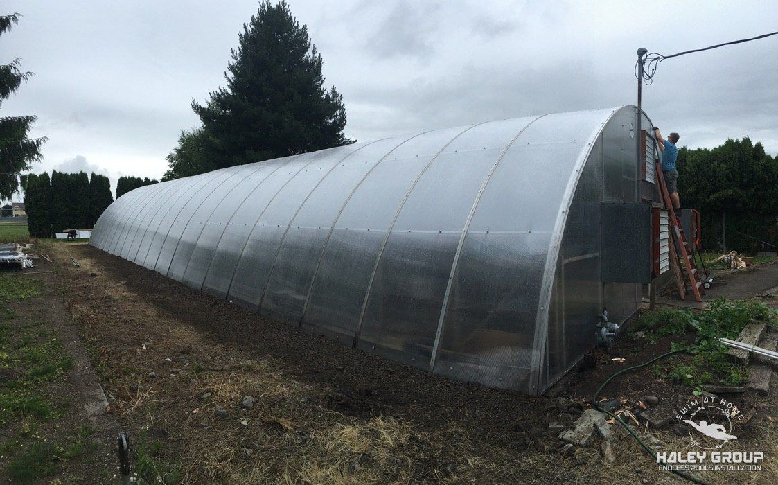 Long arched polycarbonate greenhouse, with a crew member working at the end wall