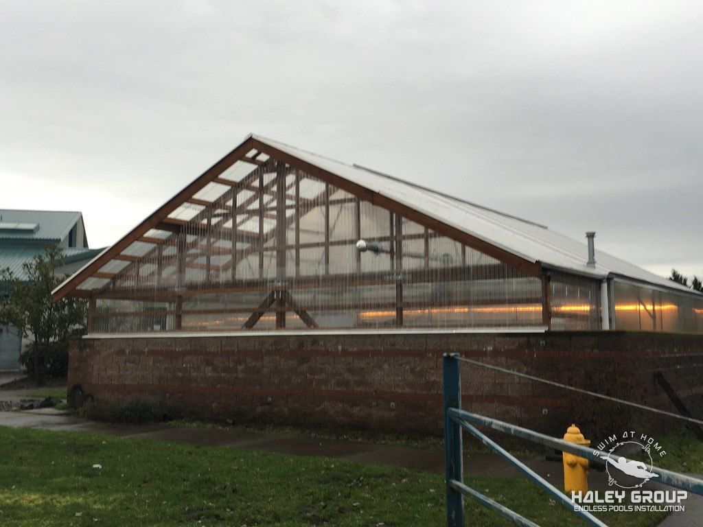 Timber-framed gable greenhouse with clear panels on a block wall