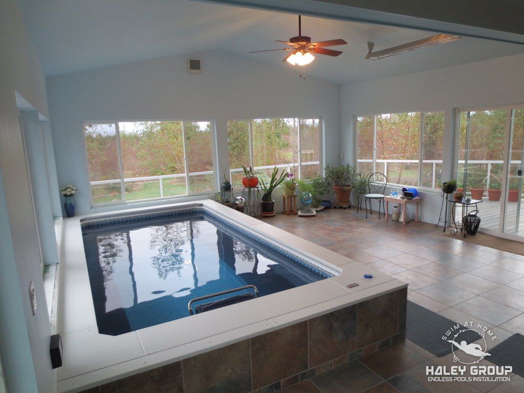 Bright pool sunroom with tile floor, tiled pool surround and walls of windows