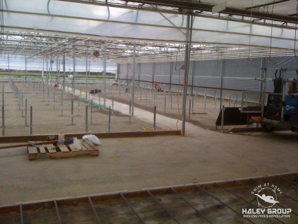 Commercial greenhouse range interior with posts set and equipment on site