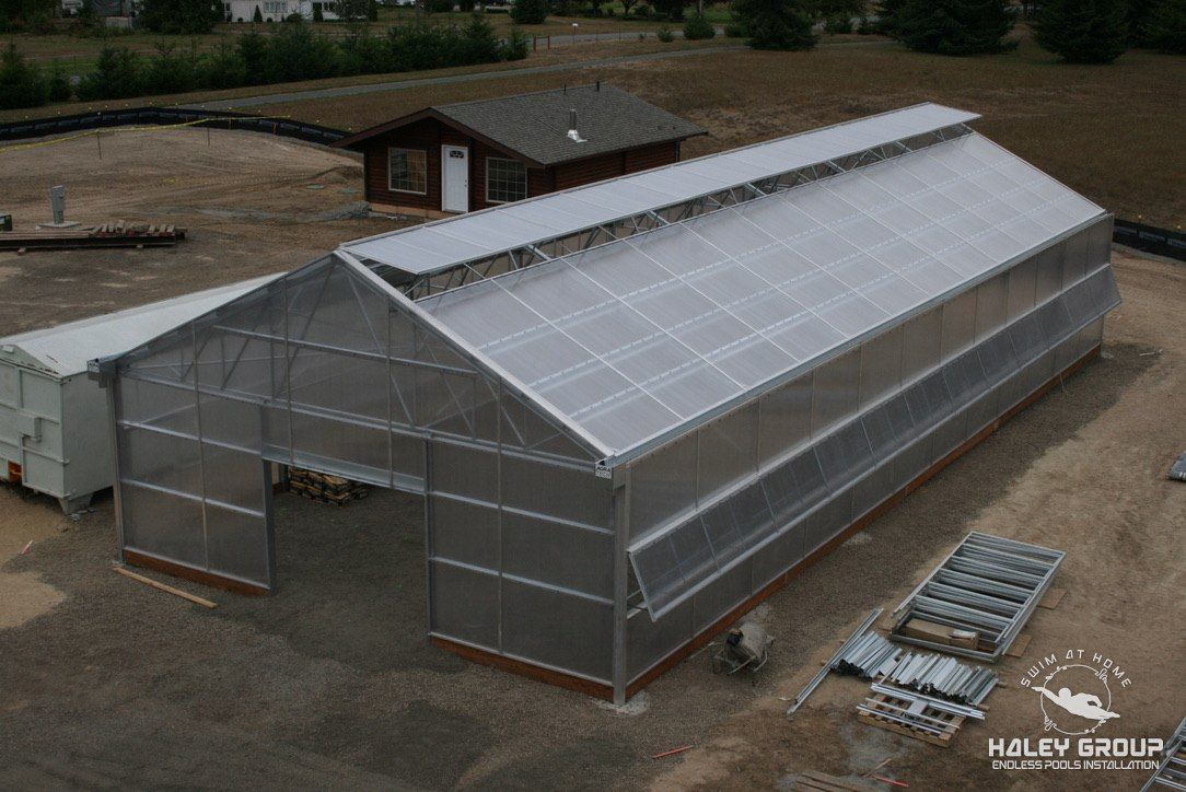 Greenhouse at a government facility in Sequim, WA: large gable-roof structure with aluminum frame, translucent multiwall panels and roof vents, during construction